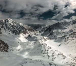 Panoramic view of a snow-capped mountain gorge with clouds, photographed on a drone