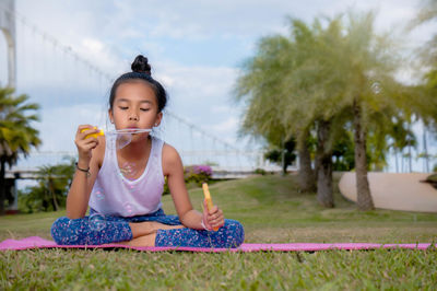 Girl blowing bubble while sitting on exercise mat