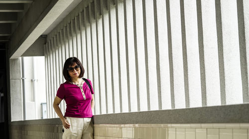 Portrait of smiling woman standing against wall