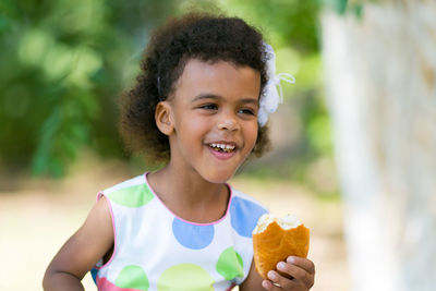 Smiling girl eating food in park