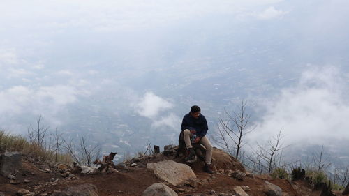 Men sitting on rock against sky