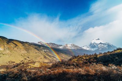 Scenic view of rainbow over mountains against sky