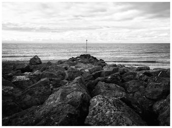 Close-up of rocks by sea against sky