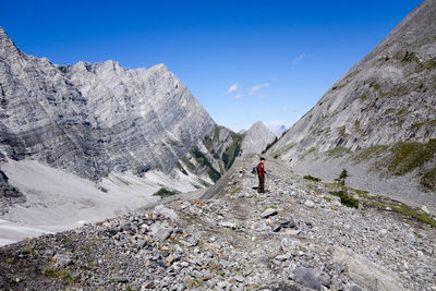 Mid distance view of woman standing amid rocky mountains against sky