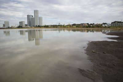 Scenic view of lake by buildings in city against sky