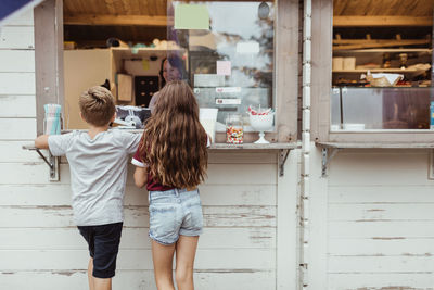 Rear view of siblings standing by concession stand during vacation