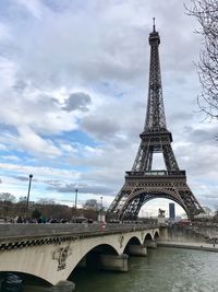 Eiffel tower in city against cloudy sky