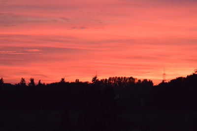 Silhouette trees against dramatic sky during sunset