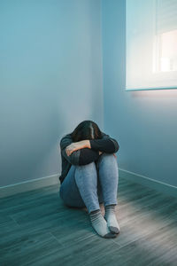 Depressed woman sitting on floor at home