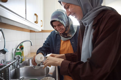 Women in headscarves cooking together for eid al-fitr at home