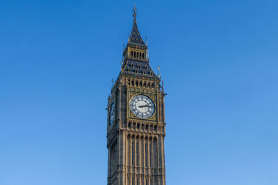 Low angle view of clock tower against blue sky