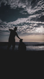 Silhouette man standing on beach against sky during sunset