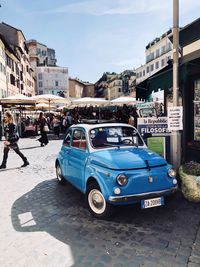Cars on city street by buildings against sky