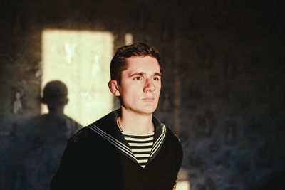 Portrait of young man standing against wall