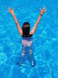 Rear view of boy swimming in pool