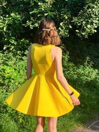 Rear view of woman standing on yellow umbrella