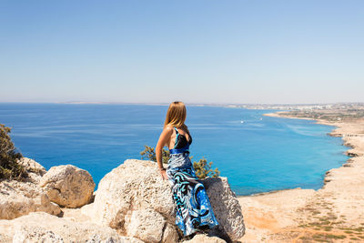 Rear view of woman looking at sea against clear sky