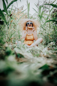 Woman eating corn while sitting by plants