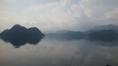 Scenic view of lake by mountains against sky