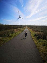 Man riding motorcycle on road amidst field against sky