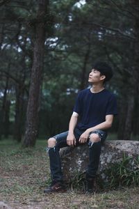 Full length of young man looking away in forest