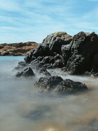 Scenic view of rocks in sea against sky