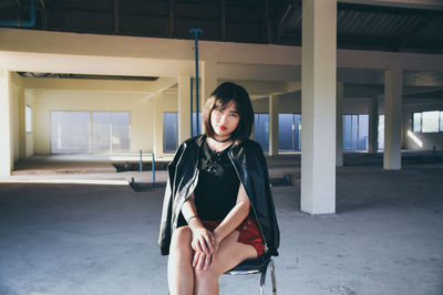 Portrait of beautiful young woman sitting on chair in building