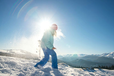 Woman on snowcapped mountain against bright sun