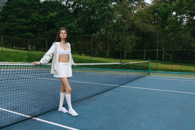 Portrait of young woman standing on tennis