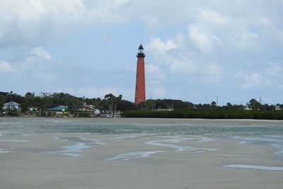 Lighthouse by sea against sky