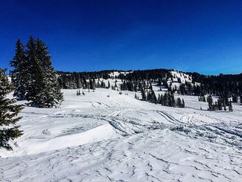 Scenic view of snow covered mountains against clear blue sky