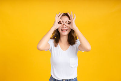 Portrait of smiling young woman against yellow background