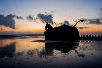 Silhouette boat on beach against sky during sunset