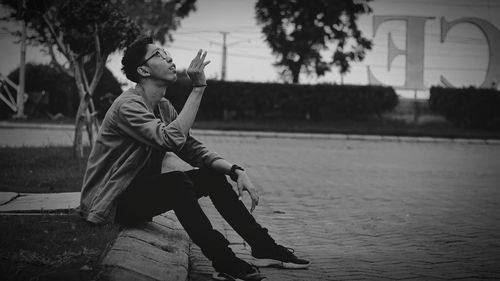 Side view of man looking away while sitting on tree