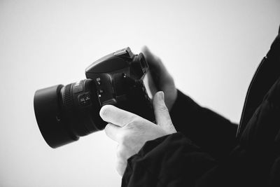 Close-up of hand holding camera against white background