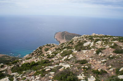 Scenic view of sea by mountain against sky