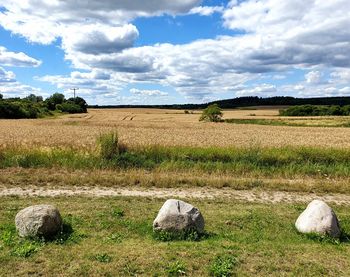 Scenic view of field against sky with three stones 