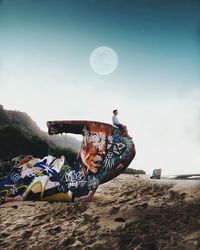 Man paragliding at beach against sky