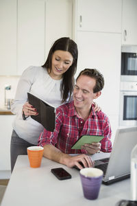 Couple using technologies at table in kitchen