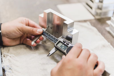 Detail of woman measuring metal workpiece