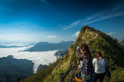 Women hiking on mountain peak against sky