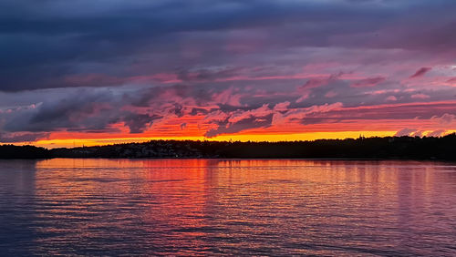 Scenic view of lake against dramatic sky during sunset