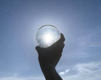 Low angle view of hand holding sun against sky