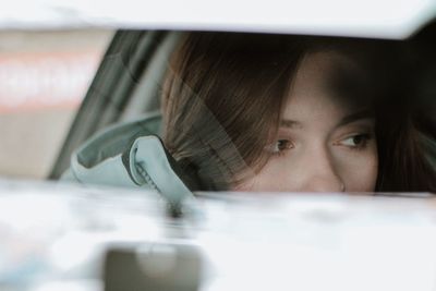 Close-up of woman reflecting rear-view mirror