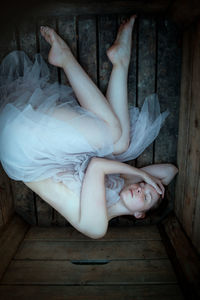 High angle view of woman lying down on wooden floor