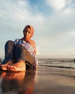 Portrait of young woman on beach against sky