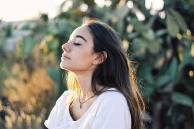 Close-up of woman with eyes closed against plants