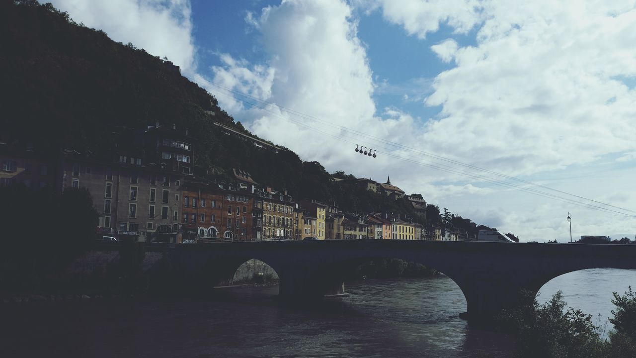 architecture, built structure, sky, connection, bridge - man made structure, transportation, building exterior, cloud - sky, bridge, tree, river, cloud, water, road, car, mountain, city, street, cloudy, street light