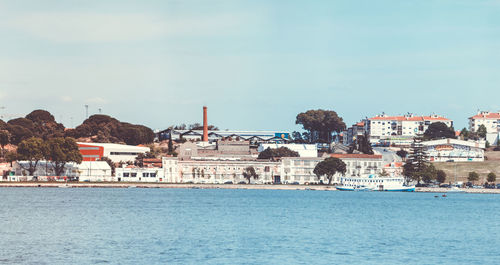 Buildings by sea against blue sky
