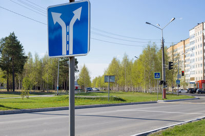 Road sign by street against clear blue sky